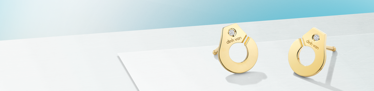 dinh van yellow gold and diamond earrings on a blue background.